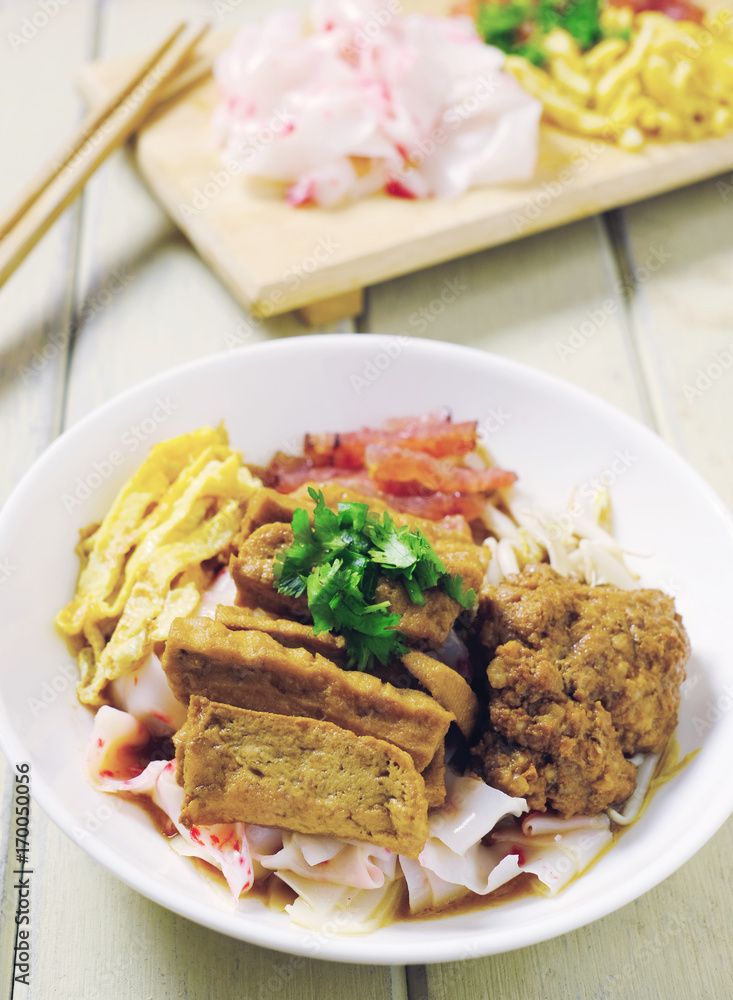 china noodle style with egg, sausage, tofu, pork ontop with gray sauce