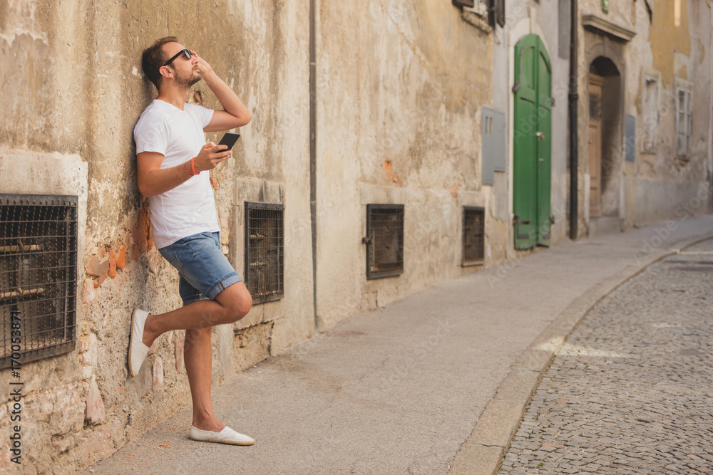 Modern guy using cellphone in the European city.