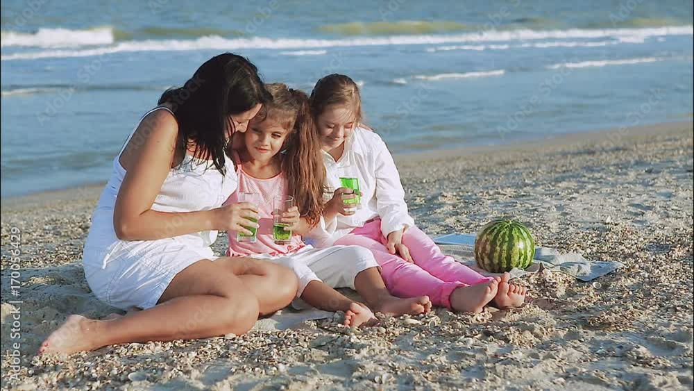 Happy family. Loving mother and two daughter on the beach With lemonade. One daughter with a disability with Down syndrome. Positive human emotions, feelings. Happy family. Loving mother and two daughter on the beach With lemonade. One daughter with a disability with Down syndrome. Positive human emotions, feelings.