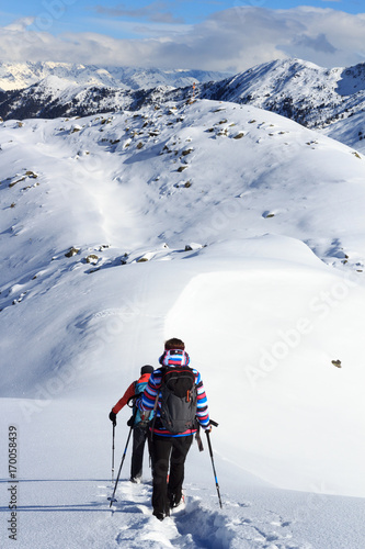 Man and woman hiking on snowshoes and mountain snow panorama with blue sky in Stubai Alps, Austria