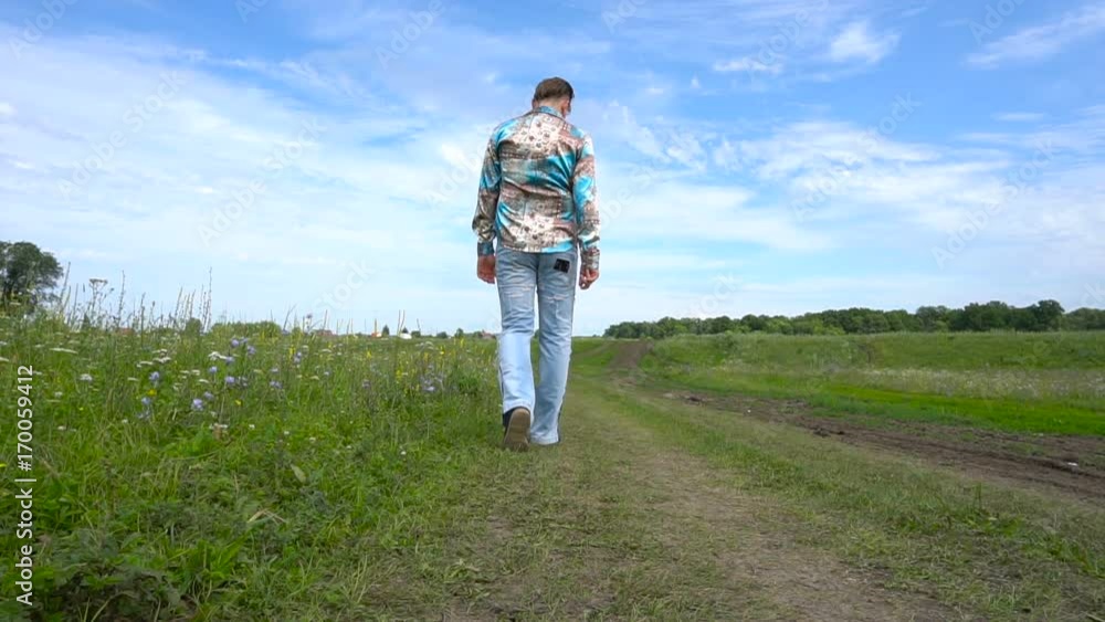 Rear view. Man go away through the field Rear view. Man go away through the field
