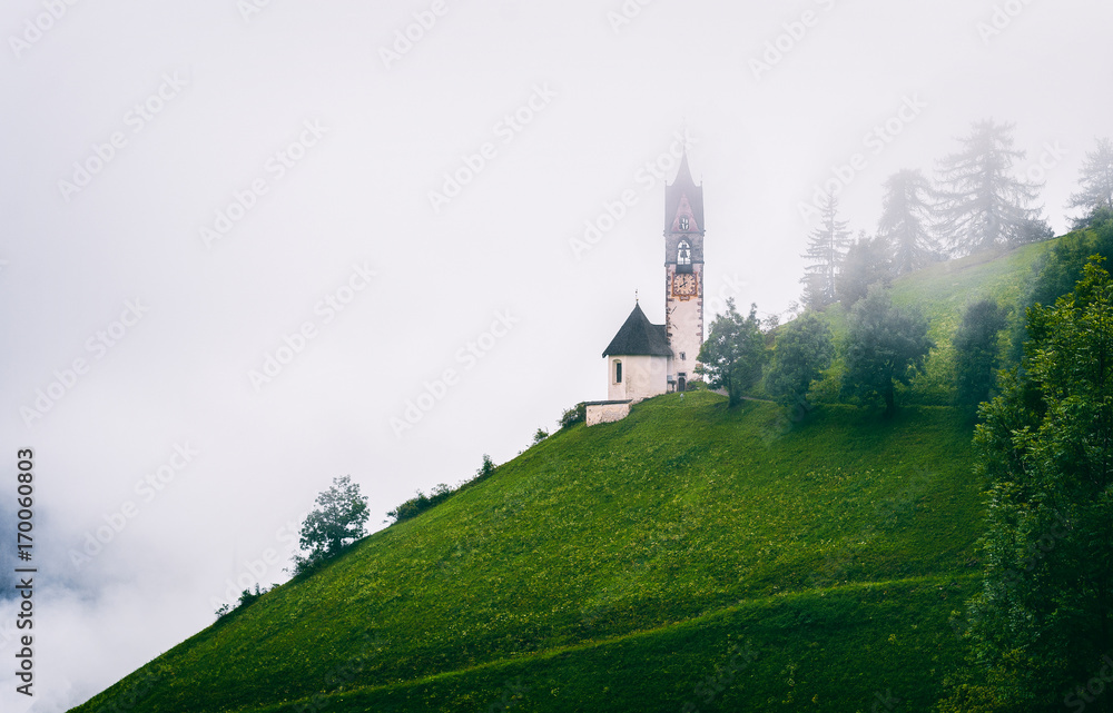 Santa Barbara church (Chiesa Santa Barbara) in La Valle in a cloud. Trentino Alto Adidge, Dolomites, Italy.