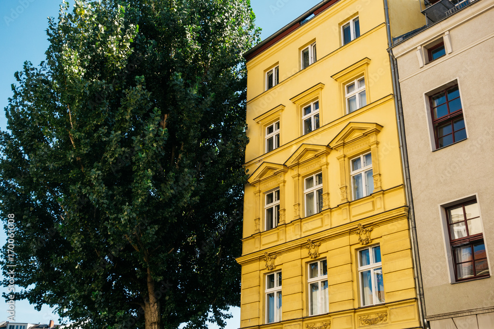 yellow apartment house next to an green tree