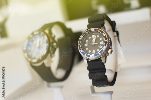 Close up of an beautiful black rubber watch. Beautiful watch in front of other watches. Lens flare in background.
