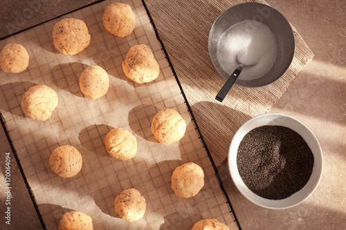 Balls of raw dough with poppy seeds on baking grid