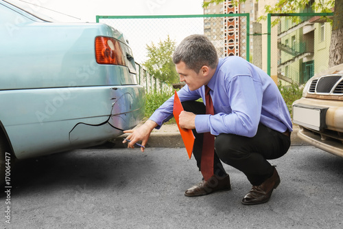 Insurance man checking broken car after accident