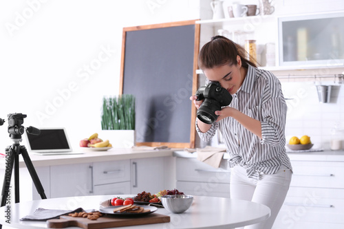 Young woman with professional camera taking still life pictures in kitchen