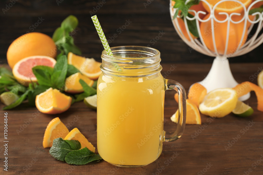 Glass jar with delicious orange juice and straw on wooden table Glass jar with delicious orange juice and straw on wooden table