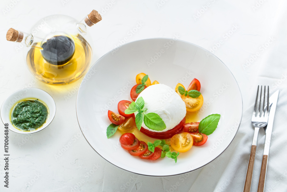 Italian appetizer caprese salad with ripe red and yellow cherry tomatoes, mozarella, fresh basil leaves and olive oil. White background. Italian appetizer caprese salad with ripe red and yellow cherry tomatoes, mozarella, fresh basil leaves and olive oil. White background.