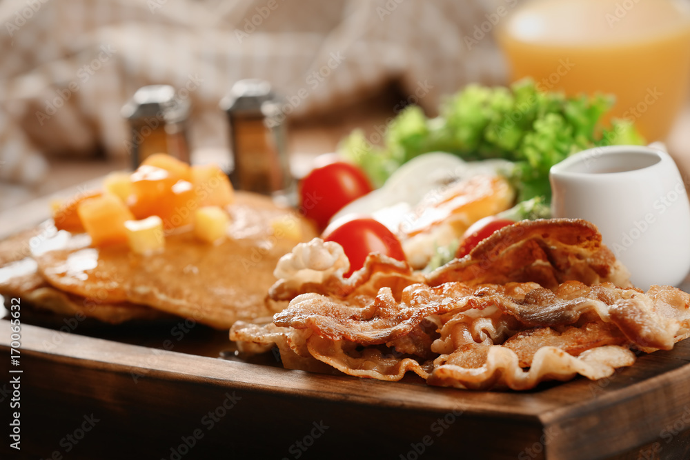 Tasty breakfast with pancakes and bacon on wooden board