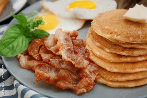 Tasty breakfast with fried eggs, pancakes and bacon on plate