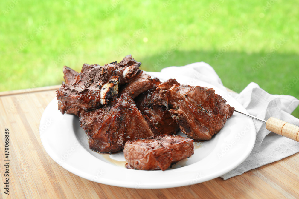 Plate with appetizing juicy spare ribs on table