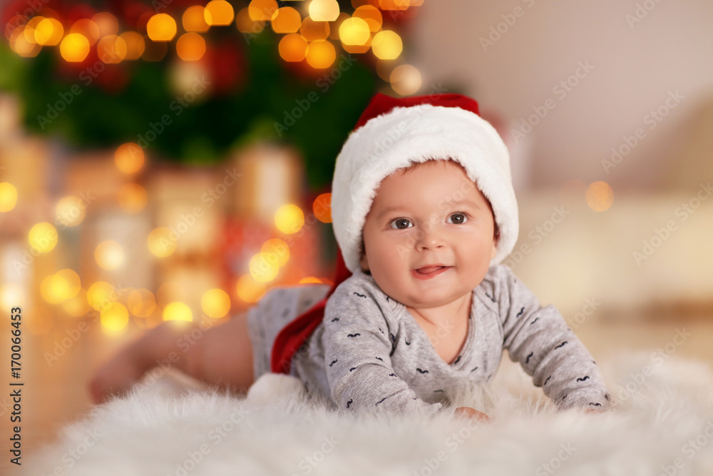 Cute little baby lying on floor against blurred Christmas lights Cute little baby lying on floor against blurred Christmas lights