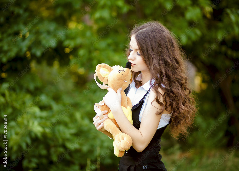 An innocent young brown-haired woman in a forest with a plush toy. - obrazy, fototapety, plakaty 