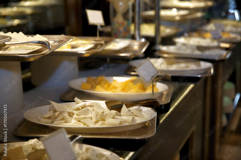 Plates with different kinds of cheese on table at buffet