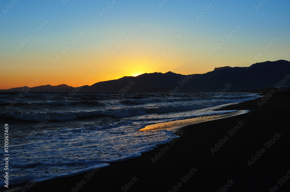 Fototapeta premium Beautiful sunset on the beach with mountains in the background
