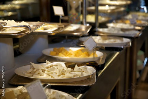 Plates with different kinds of cheese on table at buffet