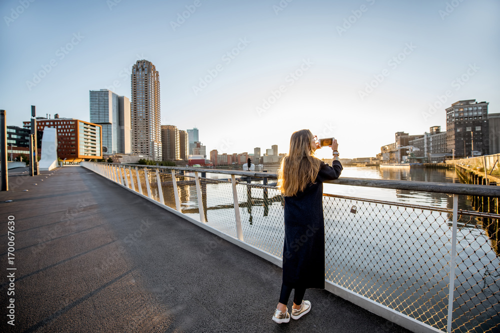 Woman enjoying modern cityscape view standing on the bridge during the morning in Roterdam city