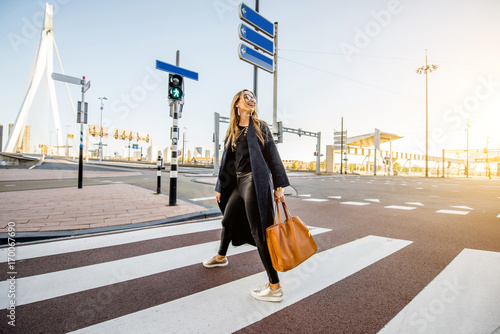 Stylish businesswoman crossing the street at the modern district during the morning in Rotterdam city