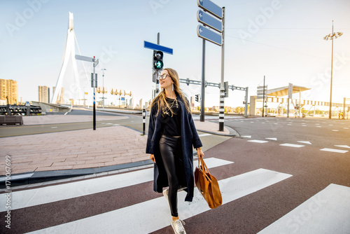 Stylish businesswoman crossing the street at the modern district during the morning in Rotterdam city