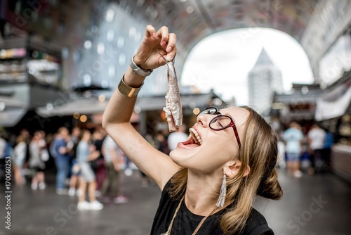 Young woman eating herring with onions traditional dutch snack in Rotterdam market