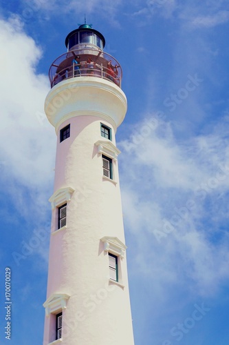 Island Lighthouse with Beautiful Sky Background White Lighthouse Against a Very Blue Sky of Aruba. Tourist attraction island lookout of the Caribbean Sea. Bathed in the warmth of a turquoise sea.