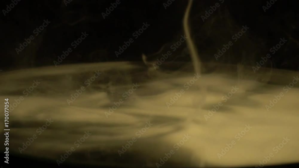 A guy makes a twister from a smoke on a round mirror A guy makes a twister from a smoke on a round mirror