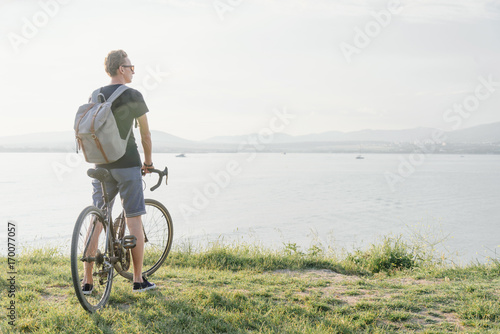 Guy with bicycle walking on coast.