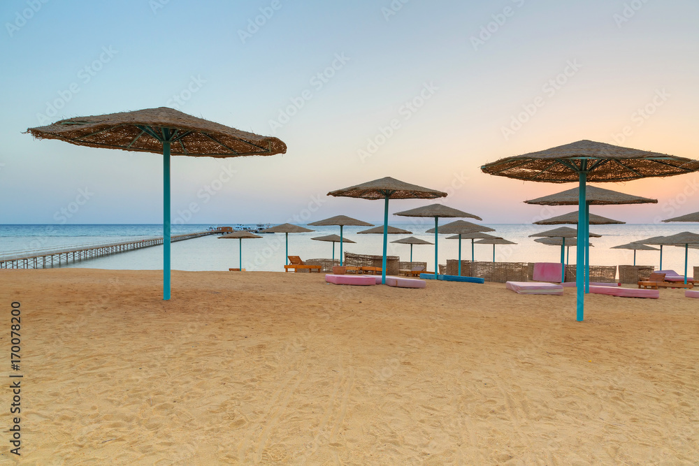 Fototapeta premium Sunrise under parasols on the beach of Red Sea, Egypt