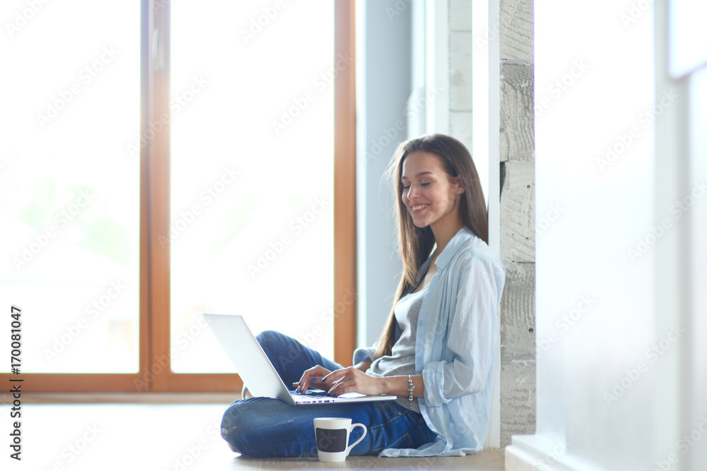 Young beautiful woman at home sitting on the floor with laptop. Young beautiful woman. Young beautiful woman at home sitting on the floor with laptop. Young beautiful woman.
