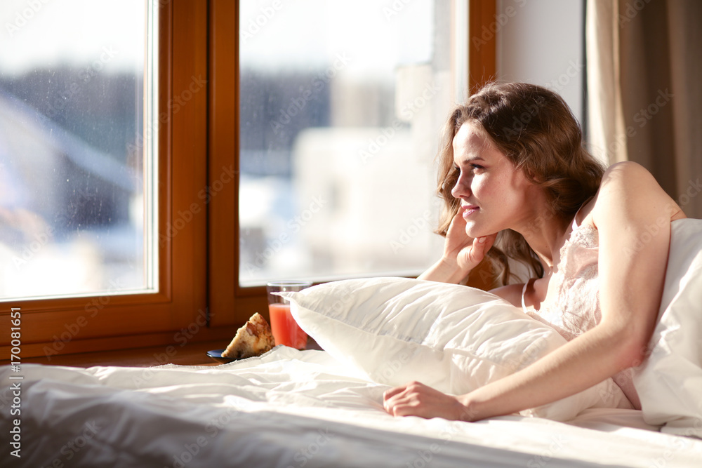 Woman lying in bed at early morning near window. Woman lying in bed at early morning near window.
