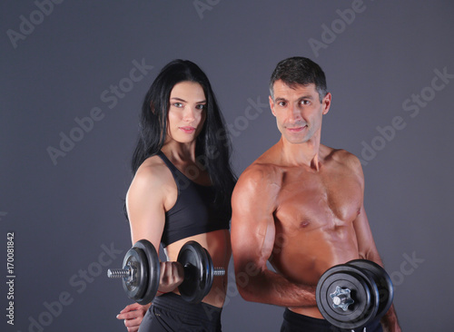 Athletic man and woman with dumb-bells. Personal fitness instructor. Personal training. Weight training. Workout.