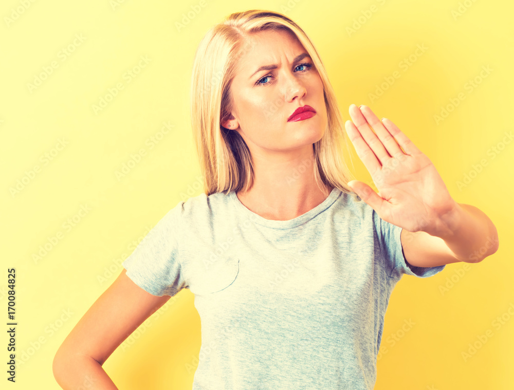 Young woman making a rejection pose on a yellow background Young woman making a rejection pose on a yellow background