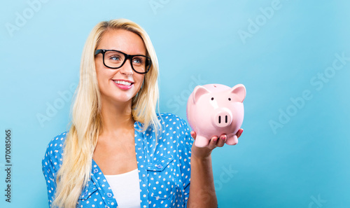 Young woman with a piggy bank on a blue background