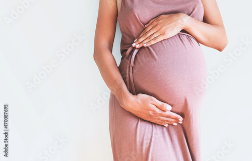 Fotografia Pregnant woman holds hands on belly. Close-up