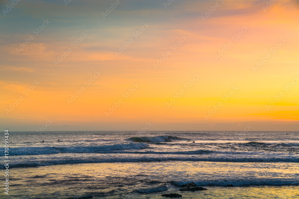 Sunset Background Ocean. Tropical Sunlight and Summer Sunset View. Colorful Background Sunset. Blue Waves near sea Resort. Isolated Sea Sunset. Surfing Beach with Surfers on the Horizon. Landscape