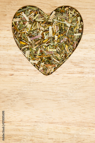 Dried herb leaves heart shaped on wooden surface