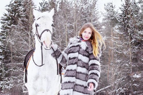 Nice girl and white horse outdoor in a winter