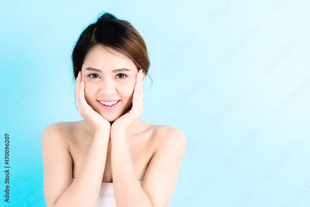 Asian young beautiful confidence woman smiling portrait touching her face over blue background. Asian young beautiful confidence woman smiling portrait touching her face over blue background.