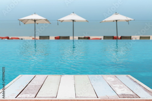 Wood table top and blurred swimming pool with sea background. - can used for display or montage your products.