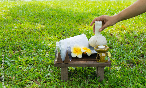 Female hand with Spa massage compress balls, herbal ball on the wooden with treaments spa, relax outdoor photo