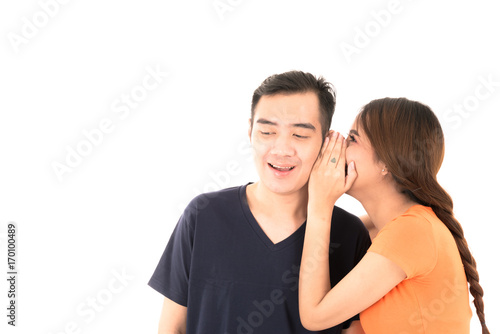 Young confident attractive Asian blue shirt man and orange woman lover couple whisper love on white background.