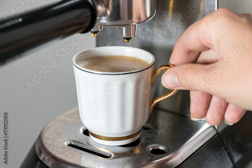 coffee machine with hand holding cup with coffee