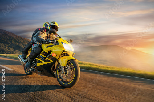 Motorbikers on sports motorbike riding in alpine landscape.