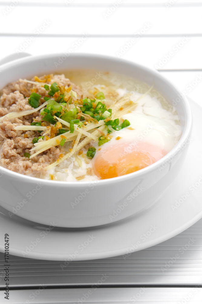 vertical pork chops rice porridge or congee with soft boiled egg and vegetable in the white bowl with spoon on the aluminium table for delicious breakfast and clean food in the morning