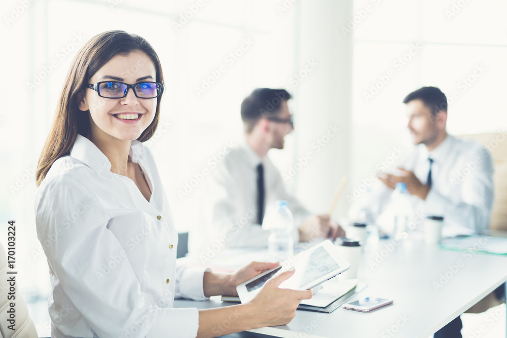 The businesswoman with a tablet sit near colleagues