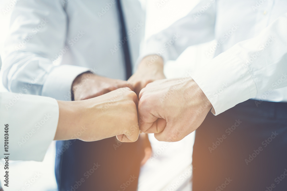 The four business people greeting with a fist