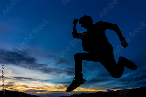 silhouette of man jumping with sunset sky for background
