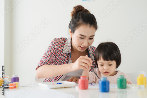 A happy family is painting. Mom help her daughter drawing