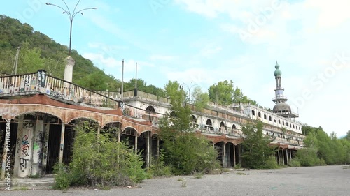 Abandoned building with murals and minaret in Consonno, Italy. Rusted construction with graffiti and wild vegetation, desolate and scary place, ghost town